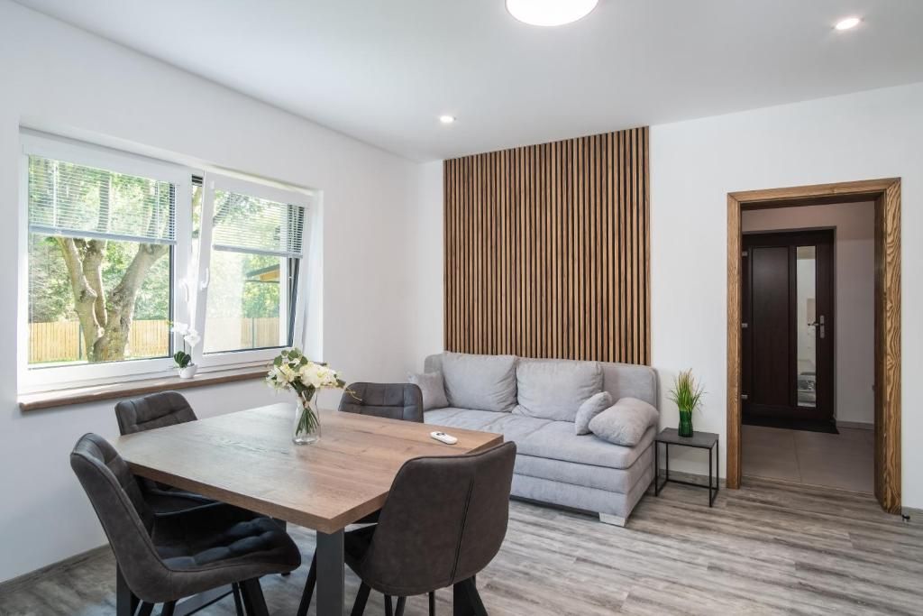 Una sala moderna con mesa de comedor, sofá y una pared decorativa de madera.