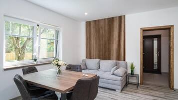 Una sala moderna con mesa de comedor, sofá y una pared decorativa de madera.
