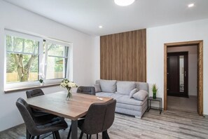 Una sala moderna con mesa de comedor, sofá y una pared decorativa de madera.