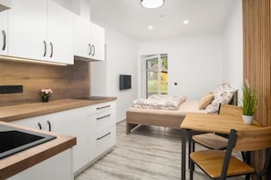 A modern kitchen with white cabinets, a wooden countertop, and a built-in stove. - RONI Apartments Krkonoše (Černý Důl)