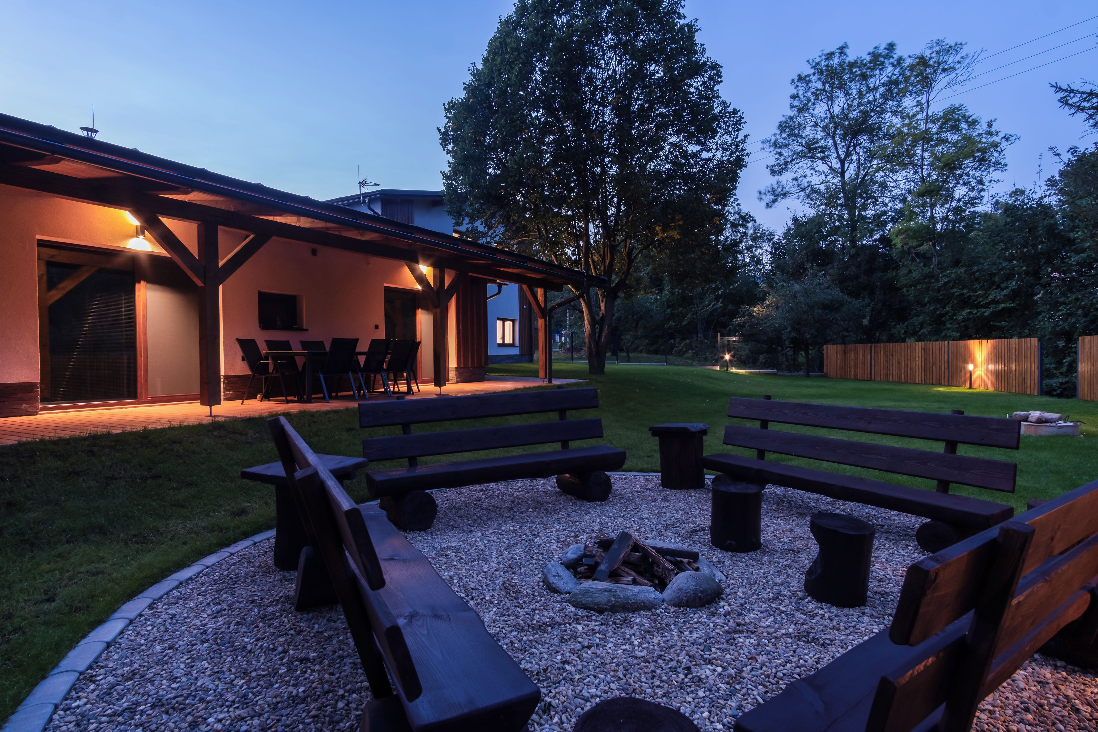 An outdoor seating area with benches and a fire pit, surrounded by a gravel circle.