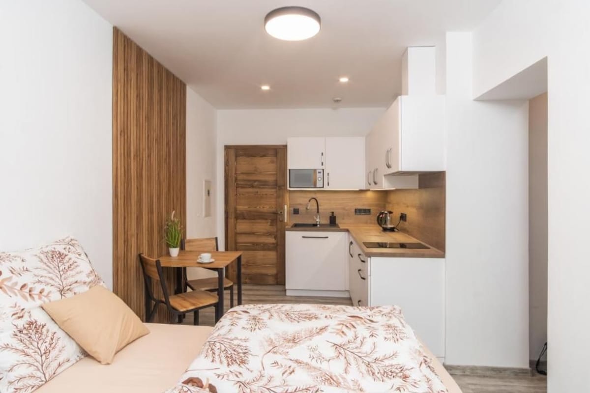 A compact room with a bed, a small dining table, and a kitchenette.