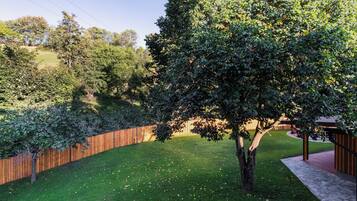 A well-maintained backyard with a wooden fence, a grassy lawn, and a variety of trees.