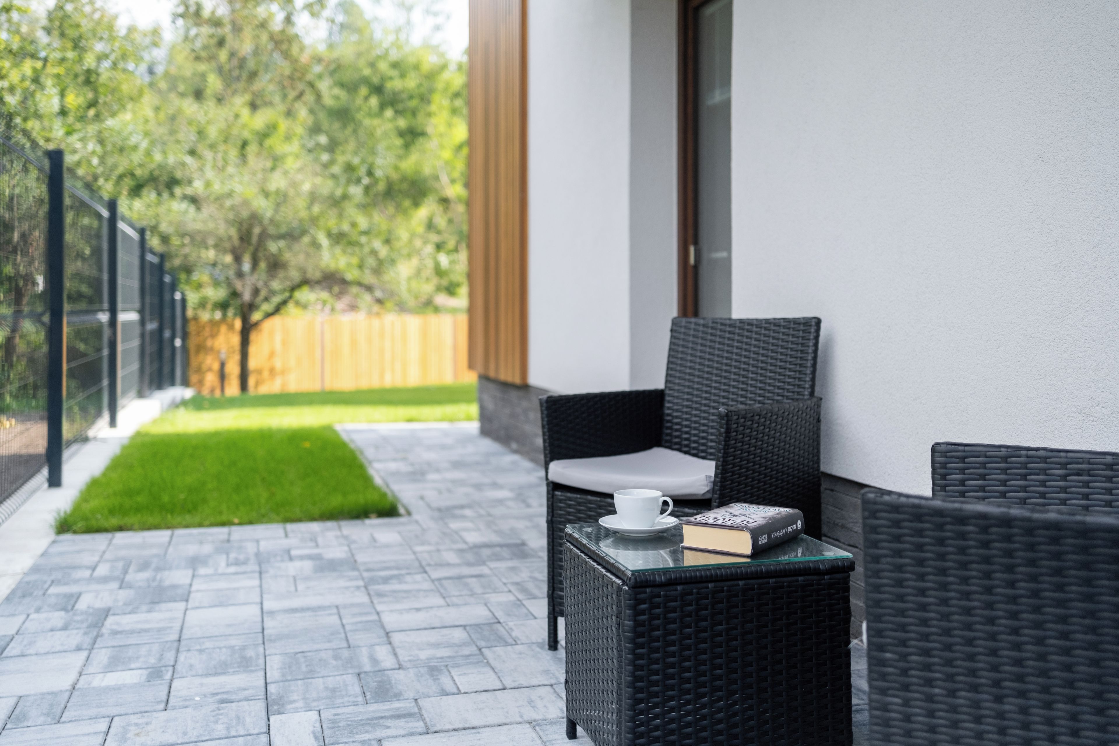 A patio with a wicker chair, a small table, and a book.