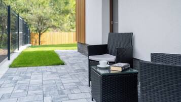 A patio with a wicker chair, a small table, and a book.