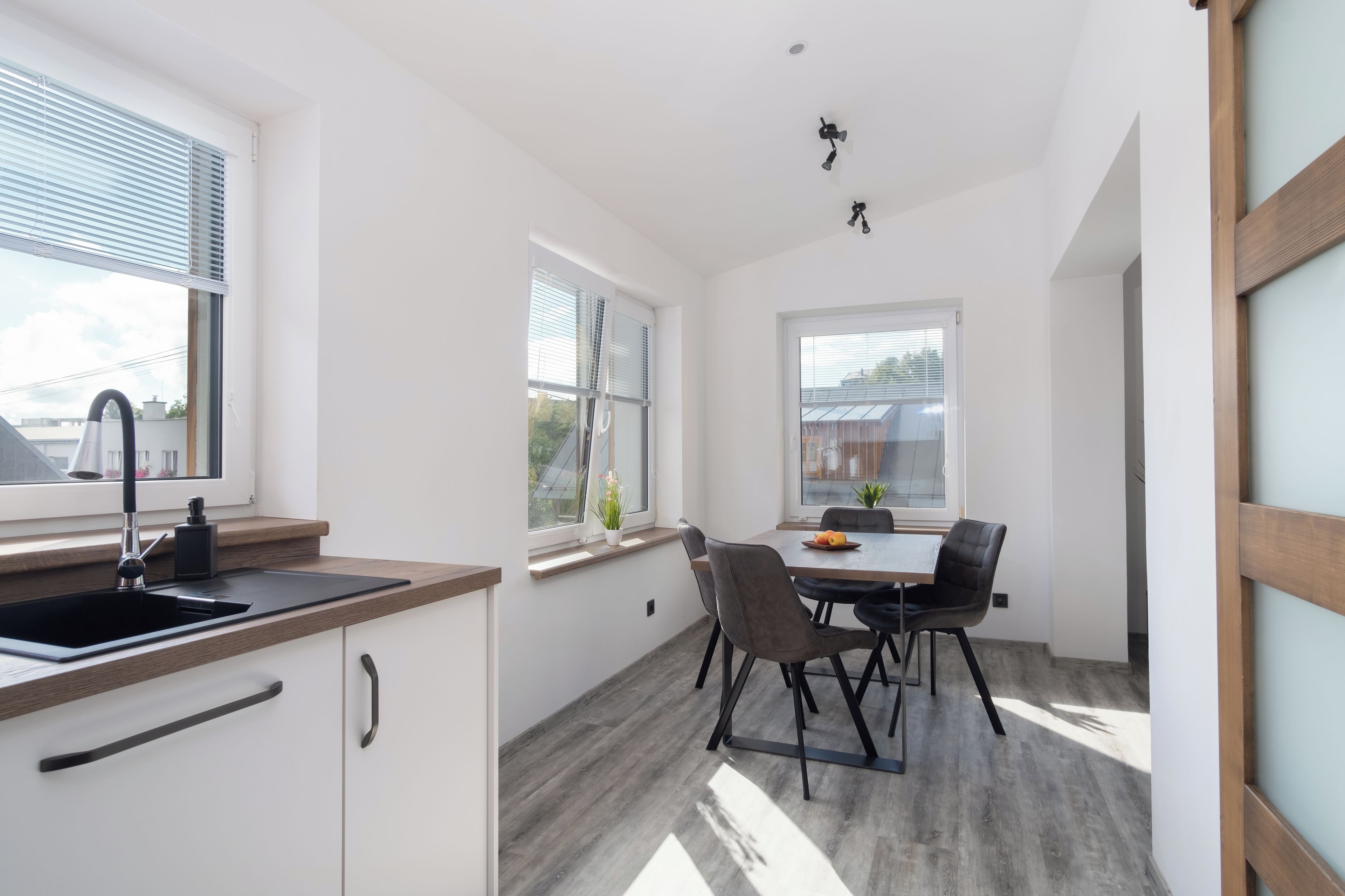 A modern kitchen with a sink, cabinets, and a dining area with a table and chairs.
