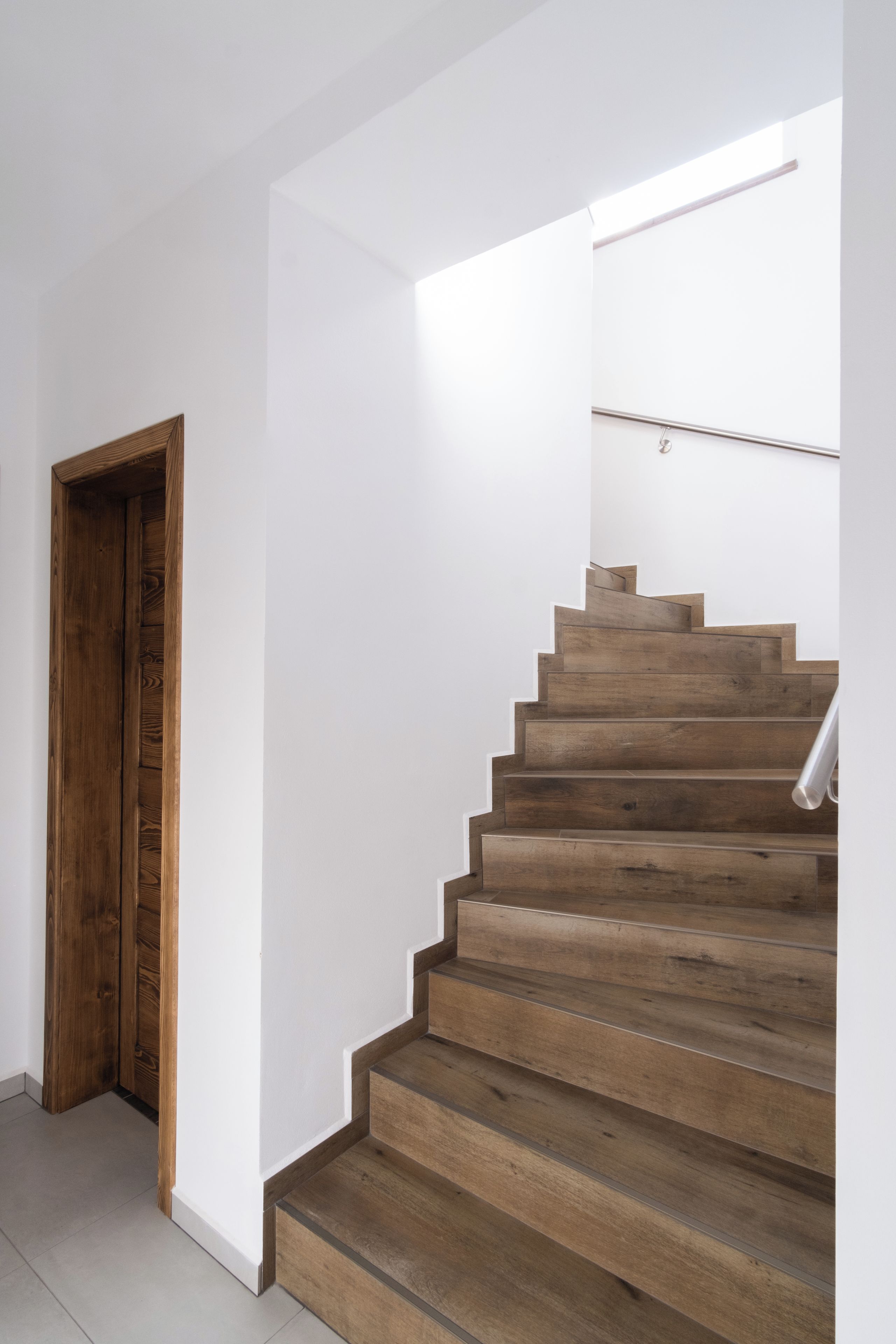 A wooden staircase with a handrail, leading to a landing with a light fixture.