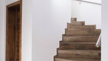 A wooden staircase with a handrail, leading to a landing with a light fixture.