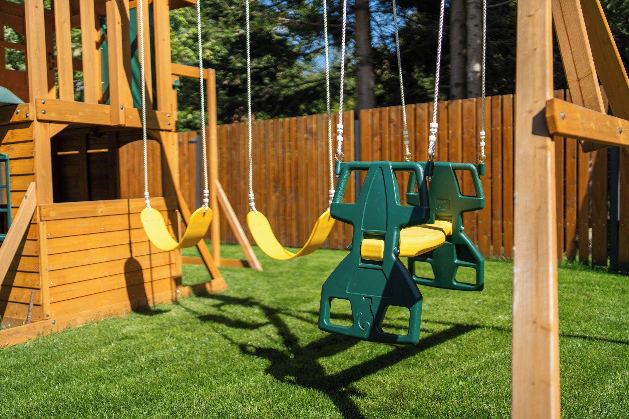 A playground with swings and a wooden playhouse.