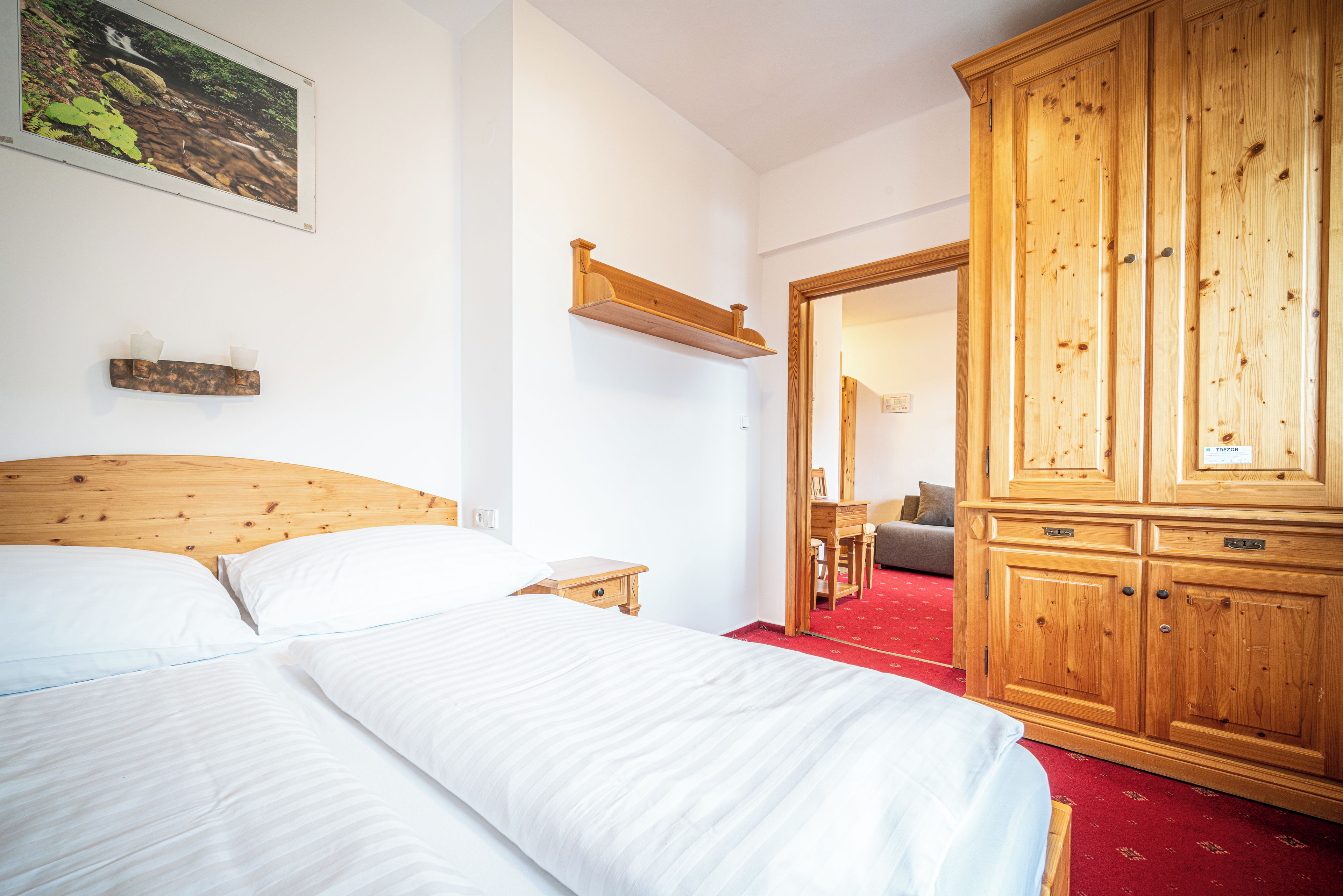 A bedroom with a wooden bed, a nightstand, a wardrobe, and a mirror.