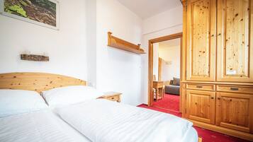A bedroom with a wooden bed, a nightstand, a wardrobe, and a mirror.
