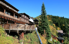 A traditional wooden chalet with balconies, a wooden bridge, and a forested hillside. - Horský hotel Sepetná (Ostravice)