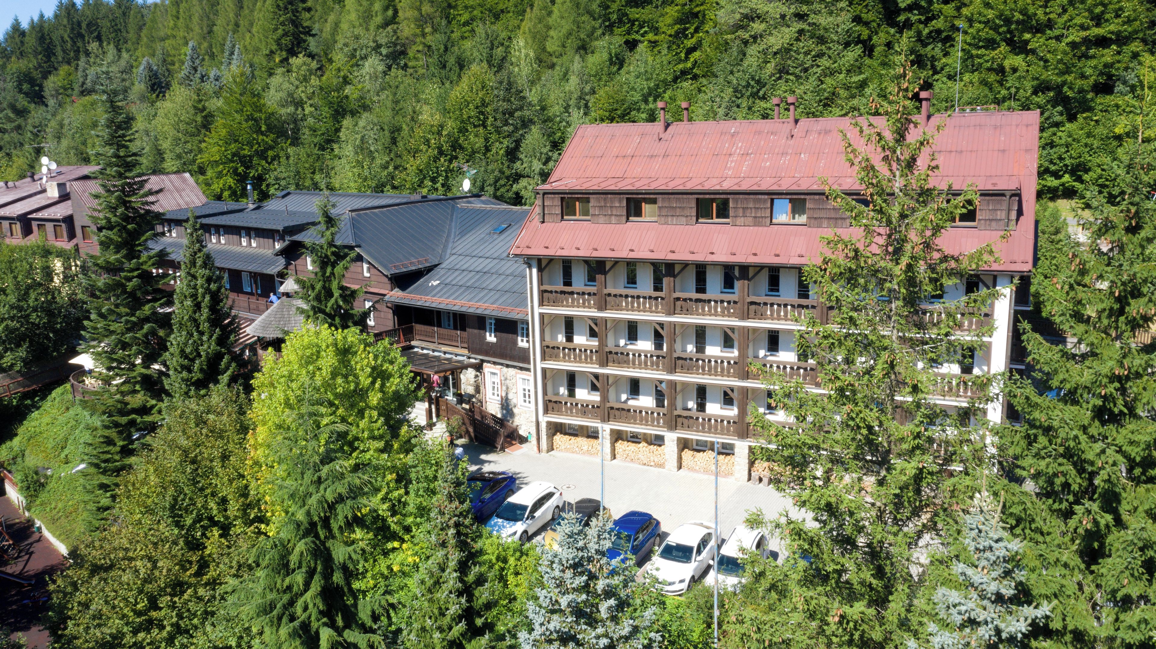 Un edificio a più piani con tetto rosso, immerso in una fitta foresta.