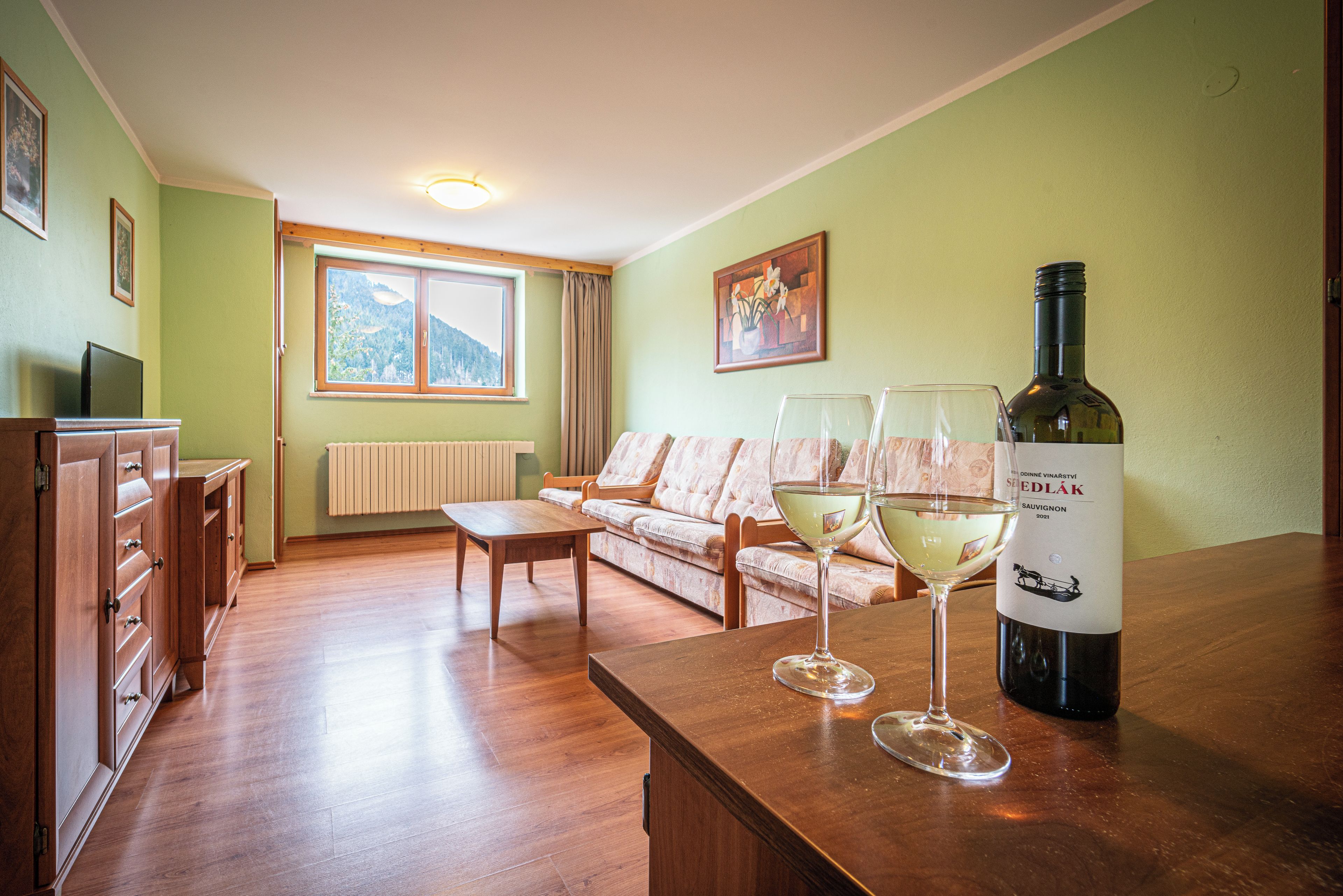 A living room with a sofa, a wooden table, and a wine bottle.
