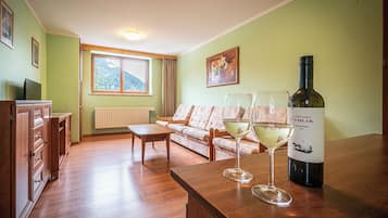 A living room with a sofa, a wooden table, and a wine bottle.
