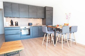 Eine moderne Küche mit dunklen Schränken, einer Holz Arbeitsplatte und einem Essbereich mit Tisch und vier Stühlen.