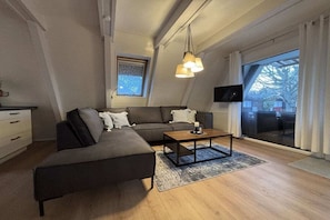 Ein modernes Wohnzimmer mit einer Couch, einem Couchtisch und einem Fernseher.