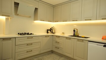 Cozinha com armários brancos, cafeteira e máquina de lavar louça.