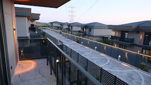 A modern residential area with a paved walkway, balconies, and a view of power lines. - Nature Quars Hotel (Silivri)
