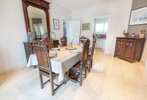 A dining room with a wooden table set for four, surrounded by chairs. A large mirror and a cabinet with decorative items are visible. - Breton family home, within walking distance of the beach – by Groom* (Ploemeur)