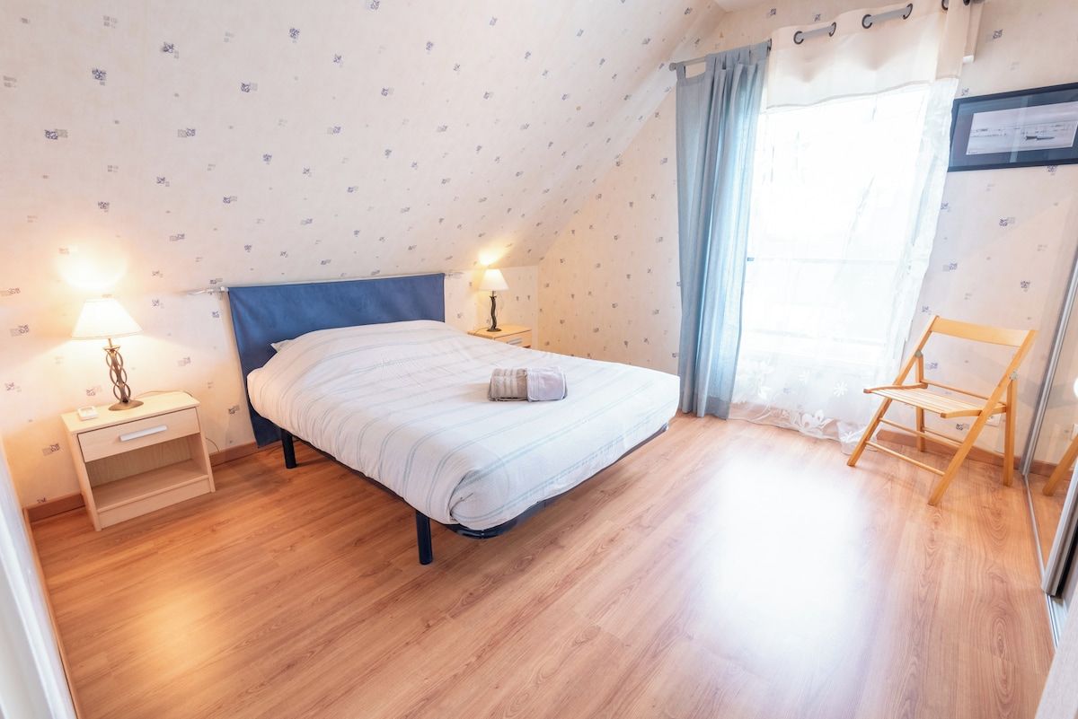 A bedroom with a bed, bedside tables, a chair, and a window with curtains.