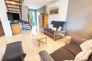 Ein modernes Wohnzimmer mit einer Couch, einem Couchtisch und einer Treppe zu einer oberen Ebene.