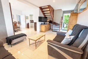Ein Wohnzimmer mit einer Couch, einem Couchtisch, einem Fernseher und einer Treppe.