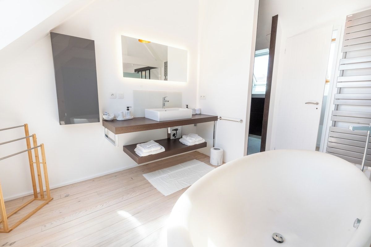 Un bagno moderno con una vasca da bagno freestanding, un mobile lavabo con specchio e un portasciugamani.