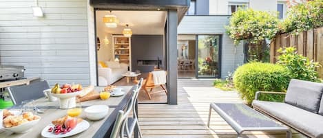 An outdoor dining area with a table set for breakfast, a barbecue grill, and a seating area with a sofa and chairs.