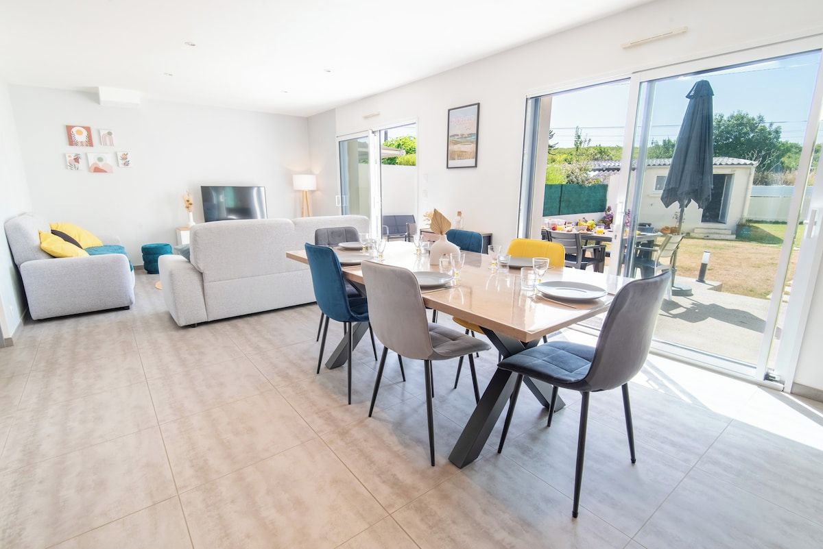 A modern living room with a dining area, a sofa set, and a TV.