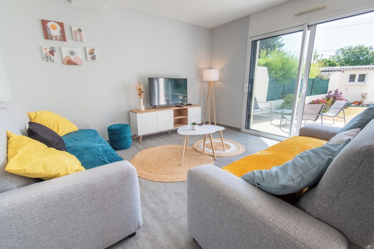 A modern living room with a sofa set, a television, a lamp, and a view of the outdoors.