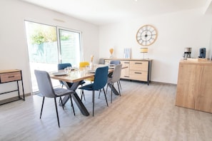 Un coin repas avec une table en bois, des chaises et une horloge au mur.