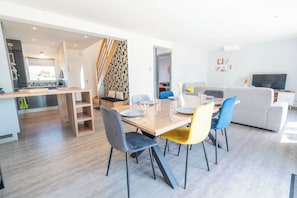 A modern living space with a dining area, kitchen, and seating area. - Charming house 2 minutes from the beaches, by Groom* (Ploemeur)
