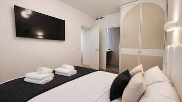 A hotel room with a bed, a flat-screen TV, a wardrobe, and a bathroom visible through an open door.
