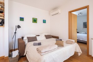 Een slaapkamer met een bed, een staande lamp en een wandgemonteerde airconditioner.