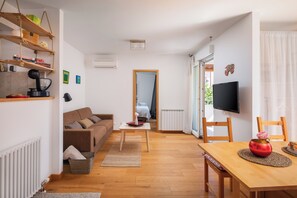 A modern living room with a wooden floor, a brown sofa, a coffee table, and a TV on a stand. - Apartment Zenta with terrace and sea view, 4 min walk to the beach (Split)