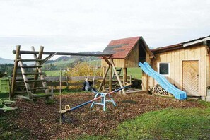 A wooden play structure with a slide, a swing set, and a climbing frame in a rural setting. - 2 on the Kling holiday farm (Fischen  im Allgäu)