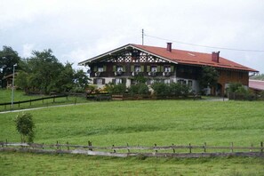 A traditional two-story house with a red roof, surrounded by a fenced grassy area. - 2 on the Kling holiday farm (Fischen  im Allgäu)