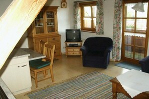 A small living room with a television, wooden furniture, and a window with curtains. - 2 on the Kling holiday farm (Fischen  im Allgäu)