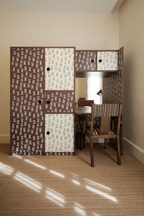 A room with a large, patterned wardrobe, a dining table with chairs, and a patterned rug. - Grand Hôtel Nord-Pinus  (Arles)