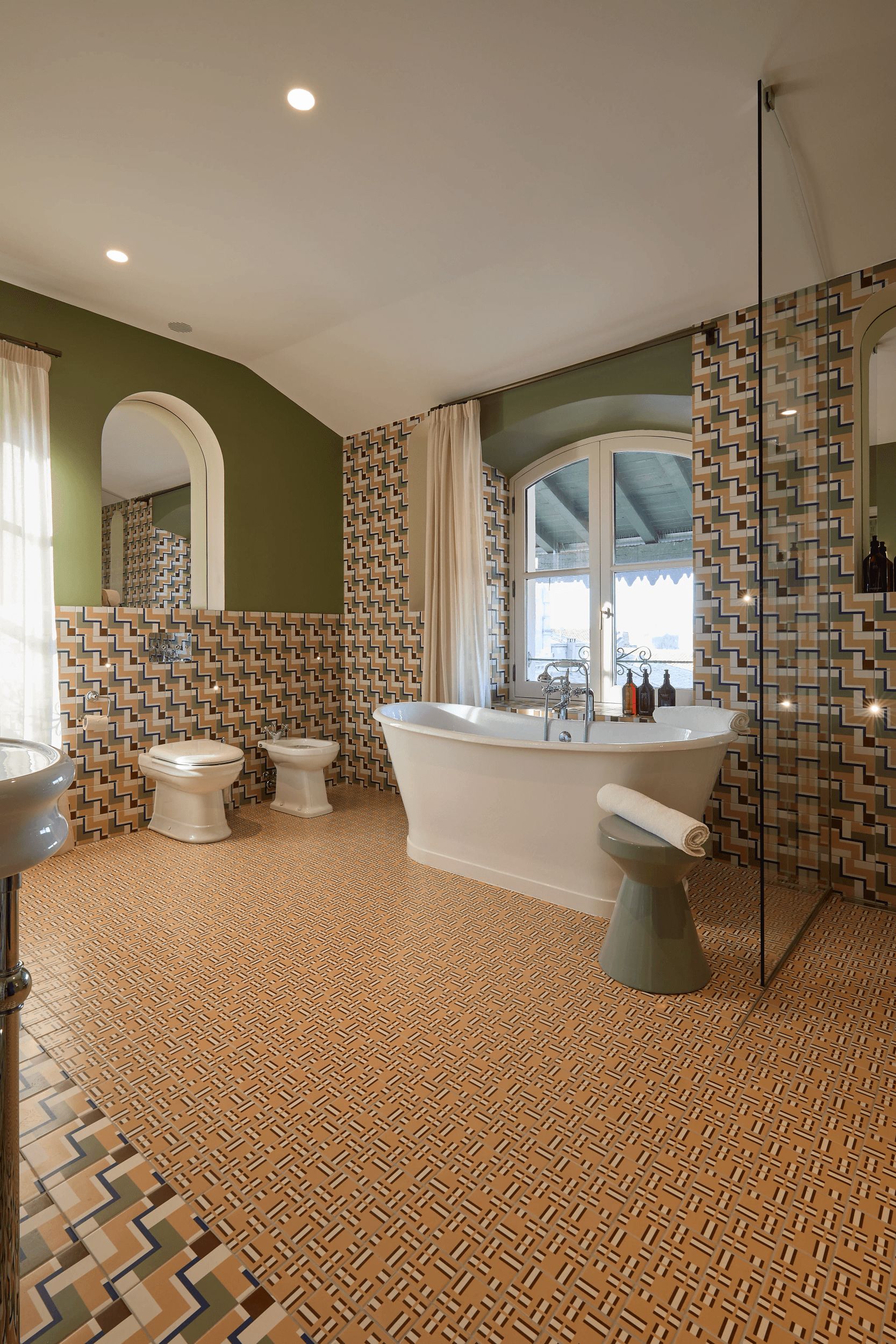 Une salle de bain avec une baignoire sur pieds, deux toilettes et un lavabo.