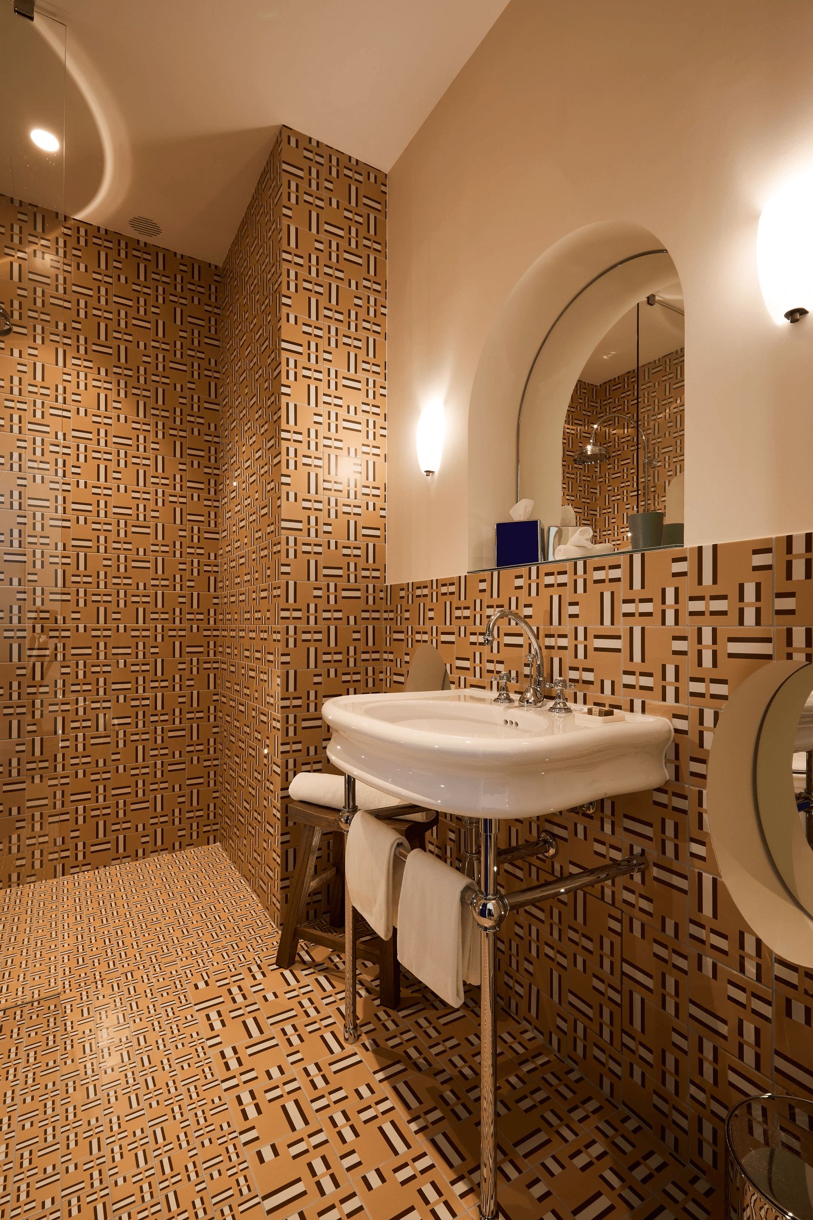 Een badkamer met betegelde vloer, een wastafel, een spiegel en een douchehoek.