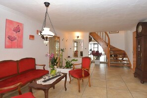 Ein Wohnzimmer mit Sofa, Sessel, Couchtisch und einer Treppe, die zu einer weiteren Ebene führt.