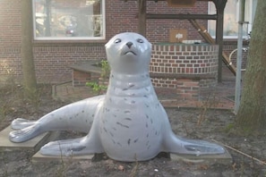 Eine Roberskulptur im Freien, im Hintergrund ein Backsteinhaus.