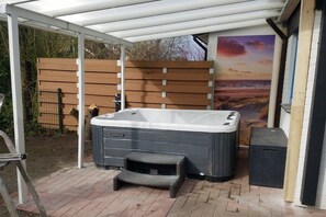 Ein Whirlpool unter einer überdachten Terrasse mit Blick auf den Sonnenuntergang.