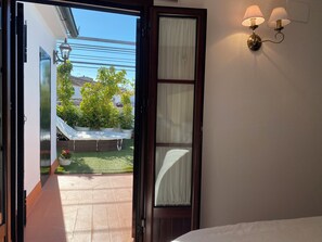 An open door leading to a balcony with a view of a garden and a building in the background. - Boutique-Eros House (Carmona)