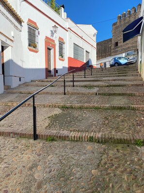 A cobblestone street leading up to a building with a red door and barred windows. - Boutique-Eros House (Carmona)