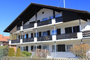 A multi-story building with balconies, a flat roof, and a clear sky. - Holiday apartment with 2 bedrooms (Fischen)