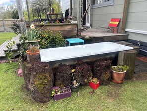 A garden area with a variety of potted plants, a wooden bench, and a metal table. - Peaceful Country Cottage between Taupo & Rotorua (Mihi)