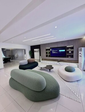 Un saló modern amb televisió de pantalla plana, seients confortables i un disseny elegant.